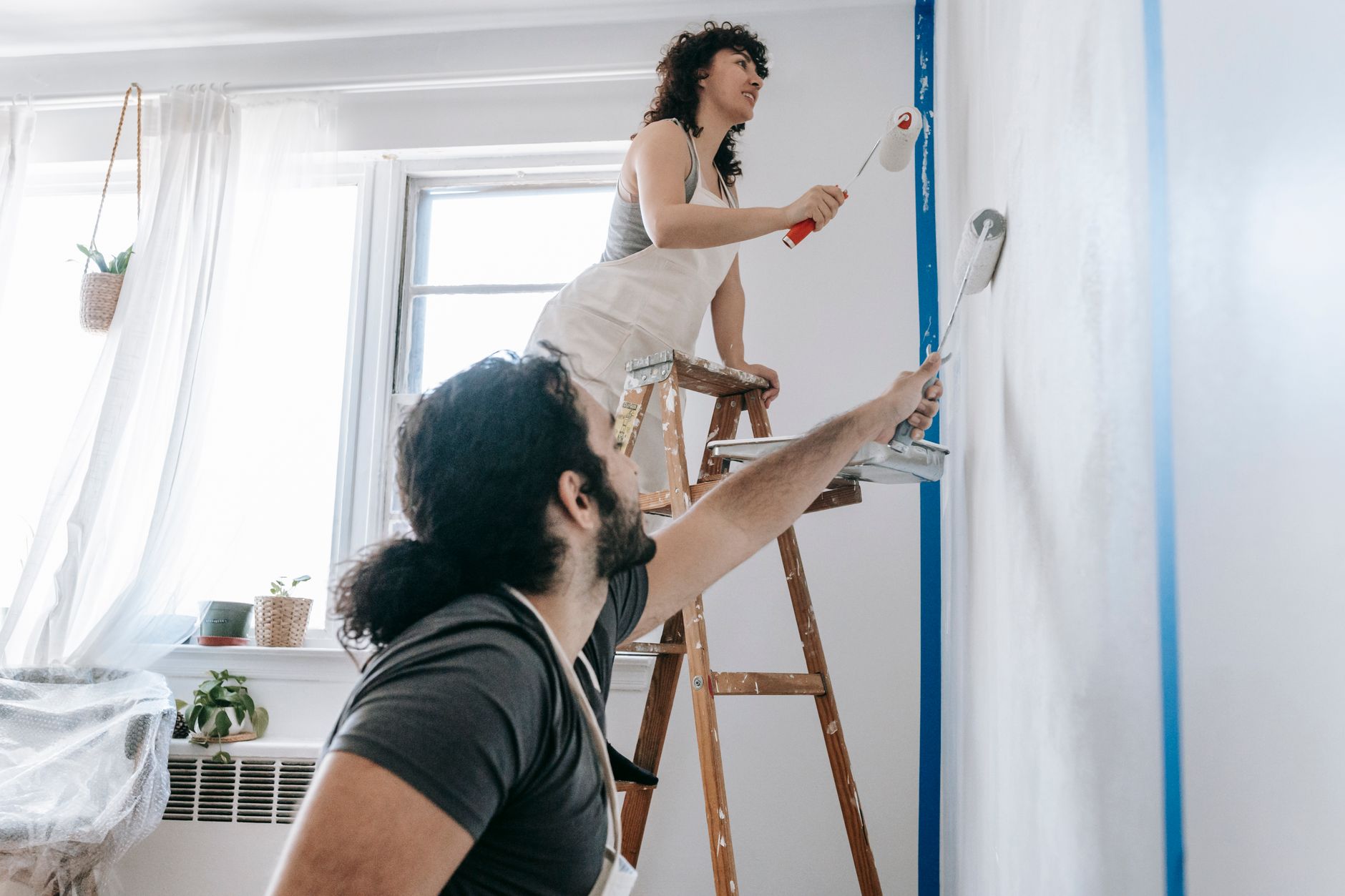 A couple engaged in a joyful home renovation, painting walls together in Pasadena, CA